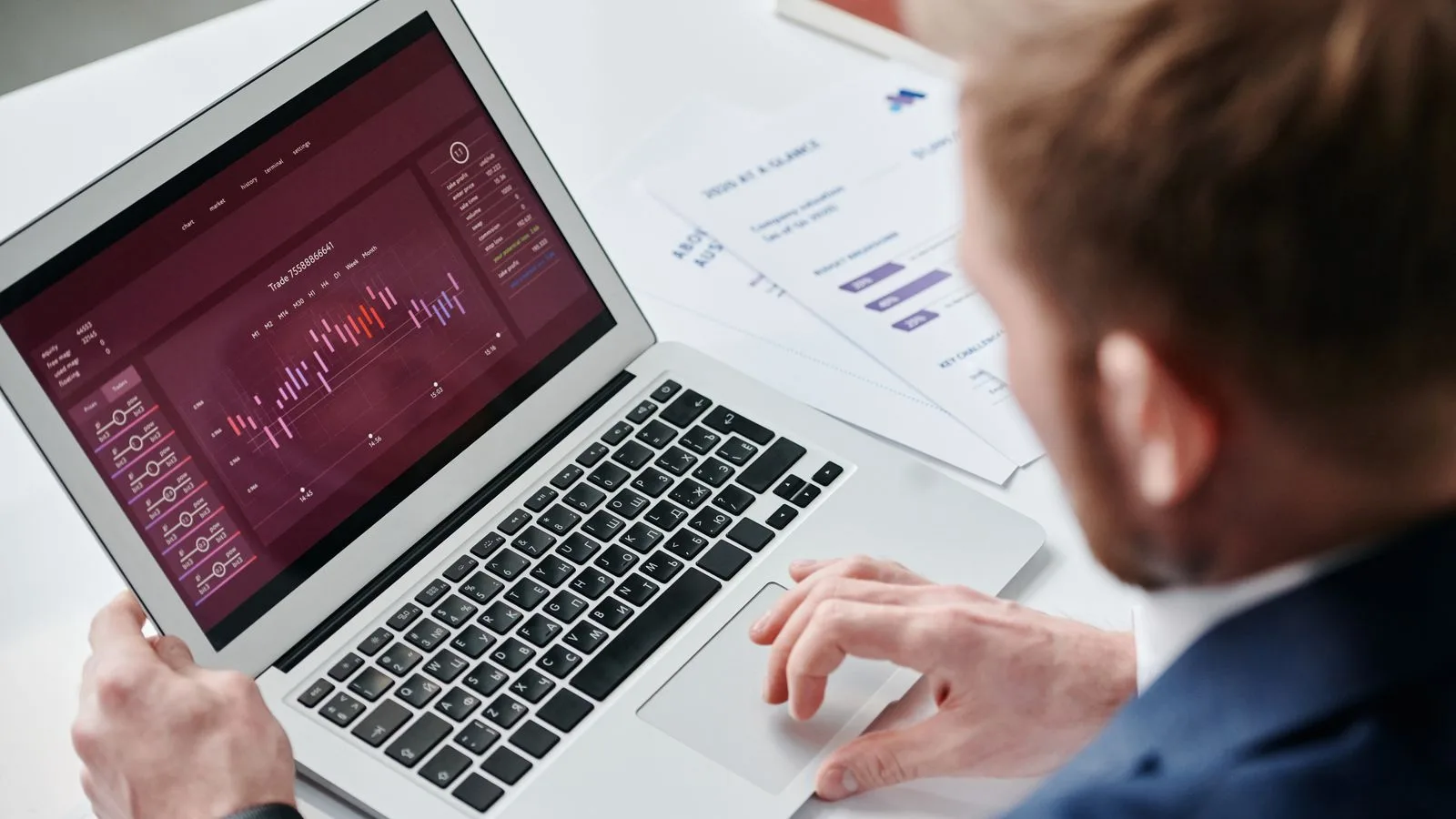 Businessman reviewing data analytics dashboard on laptop in bright office.