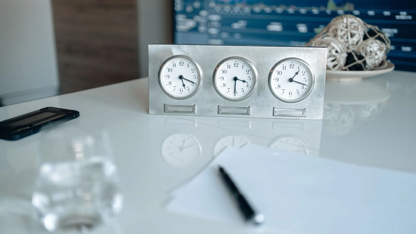 Professional workspace featuring three clocks and financial data on screen.