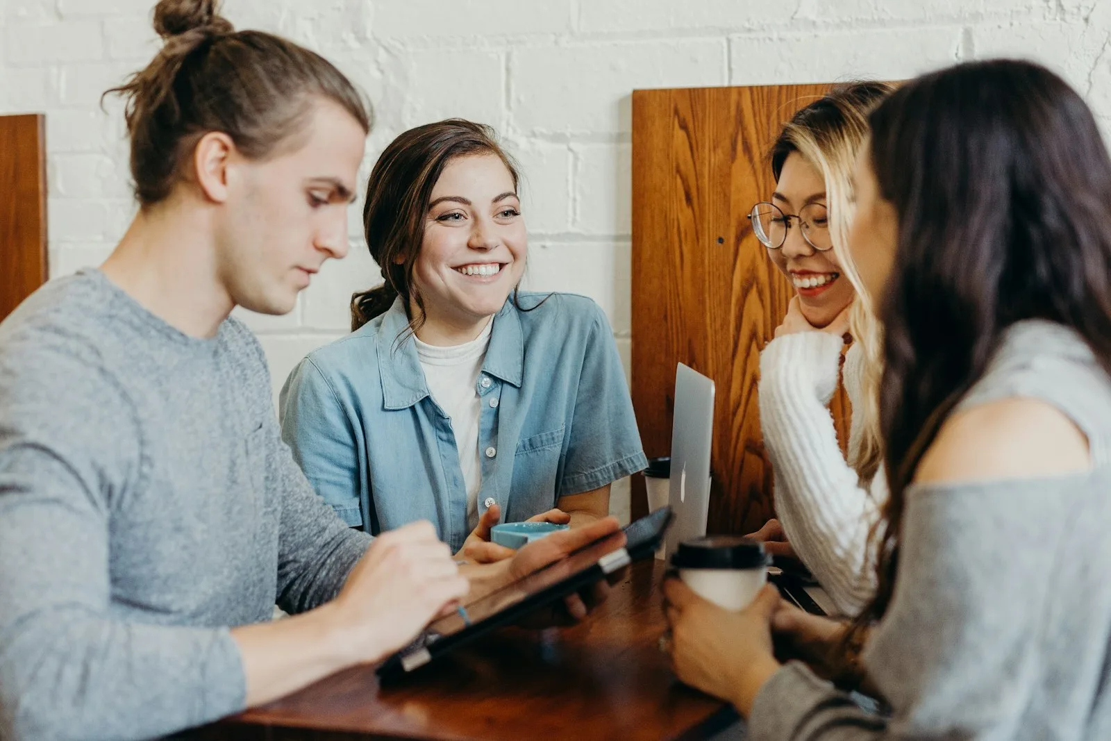 Four colleagues in a discussion around a laptop at a cafe table
