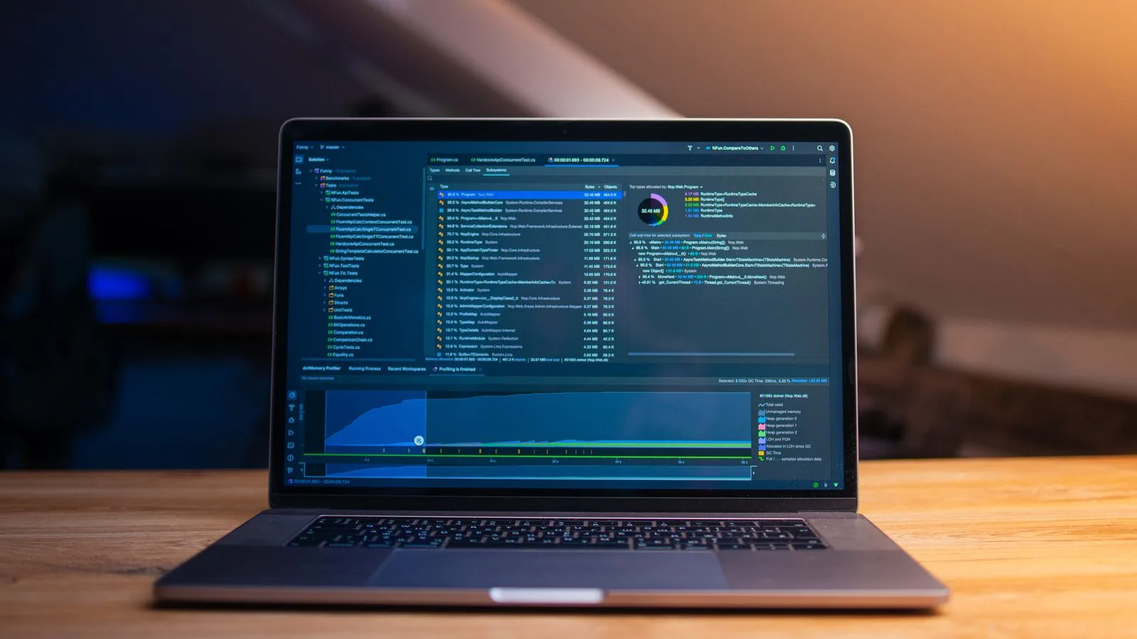 A laptop displaying code on a wooden desk, in a dimly lit workspace.