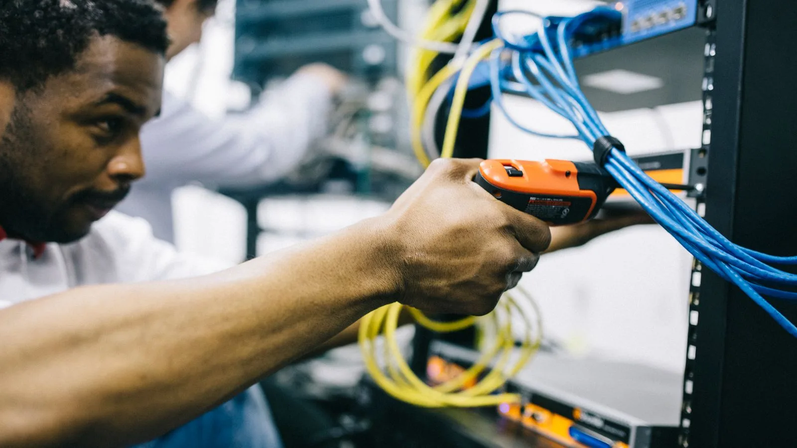 Side view crop concentrated African American engineer repairing equipment by using electric screwdriver