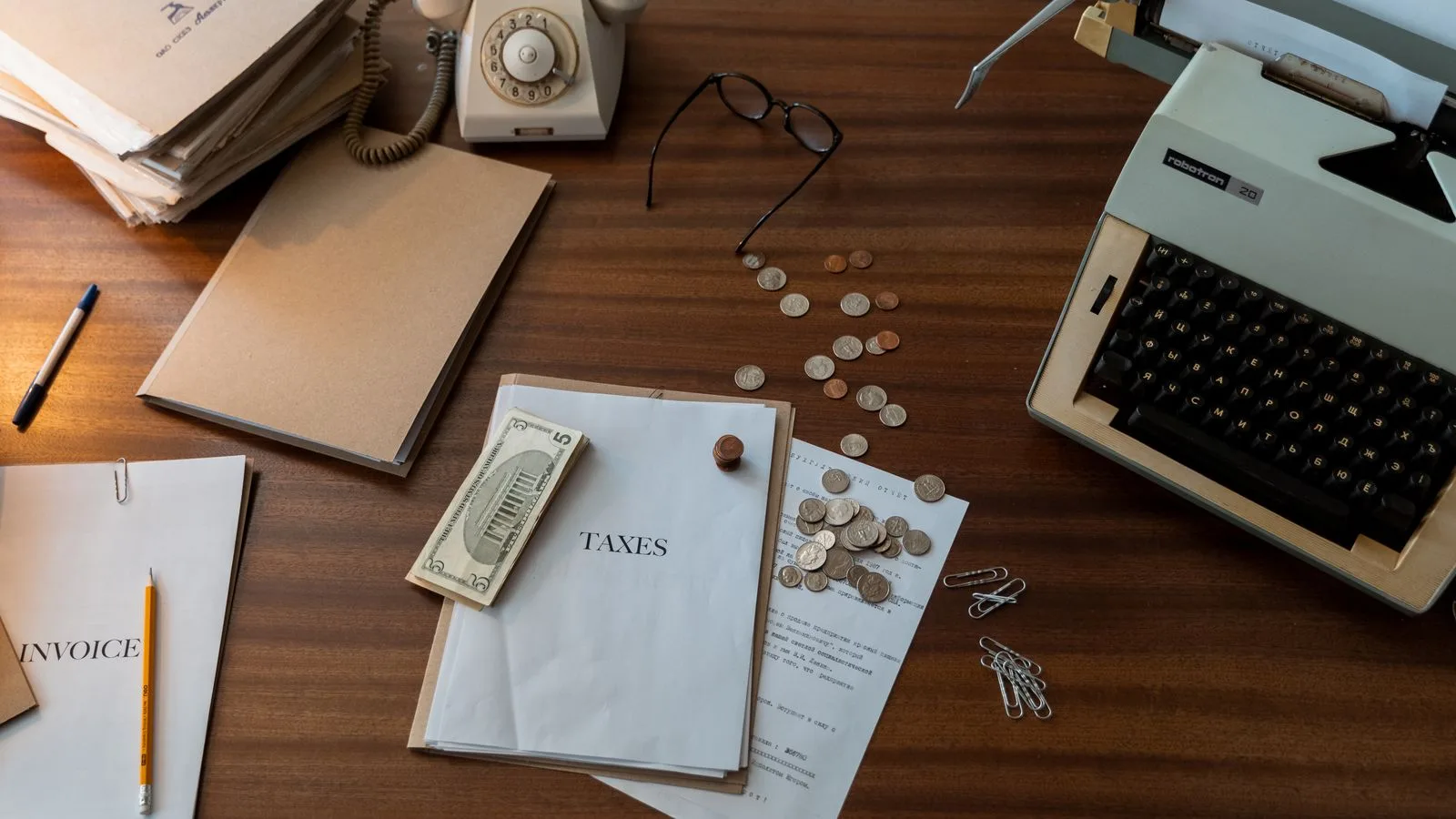 Vintage workspace with typewriter, documents, and telephone on a wooden desk, evoking a classic office setting.