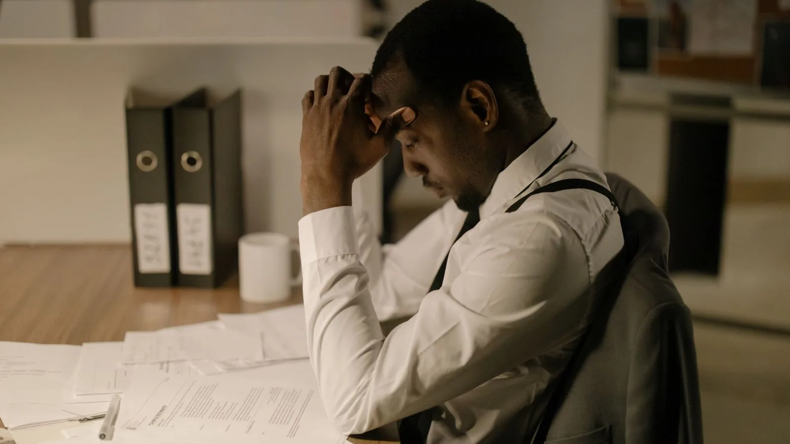 An adult man in an office is concentrating on documents, reflecting stress and focus in a work environment.